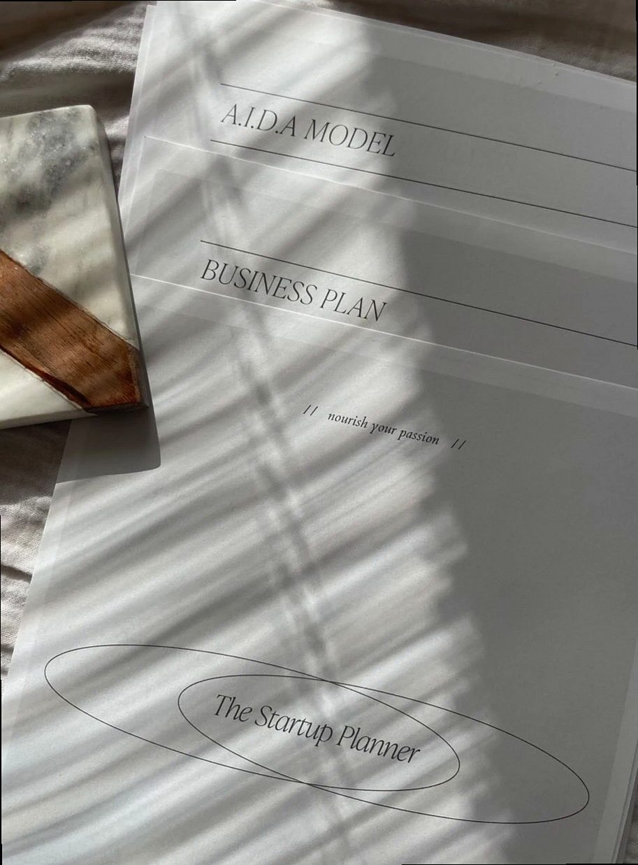Stylish planner featuring A.I.D.A model and business plan documents in soft lighting.